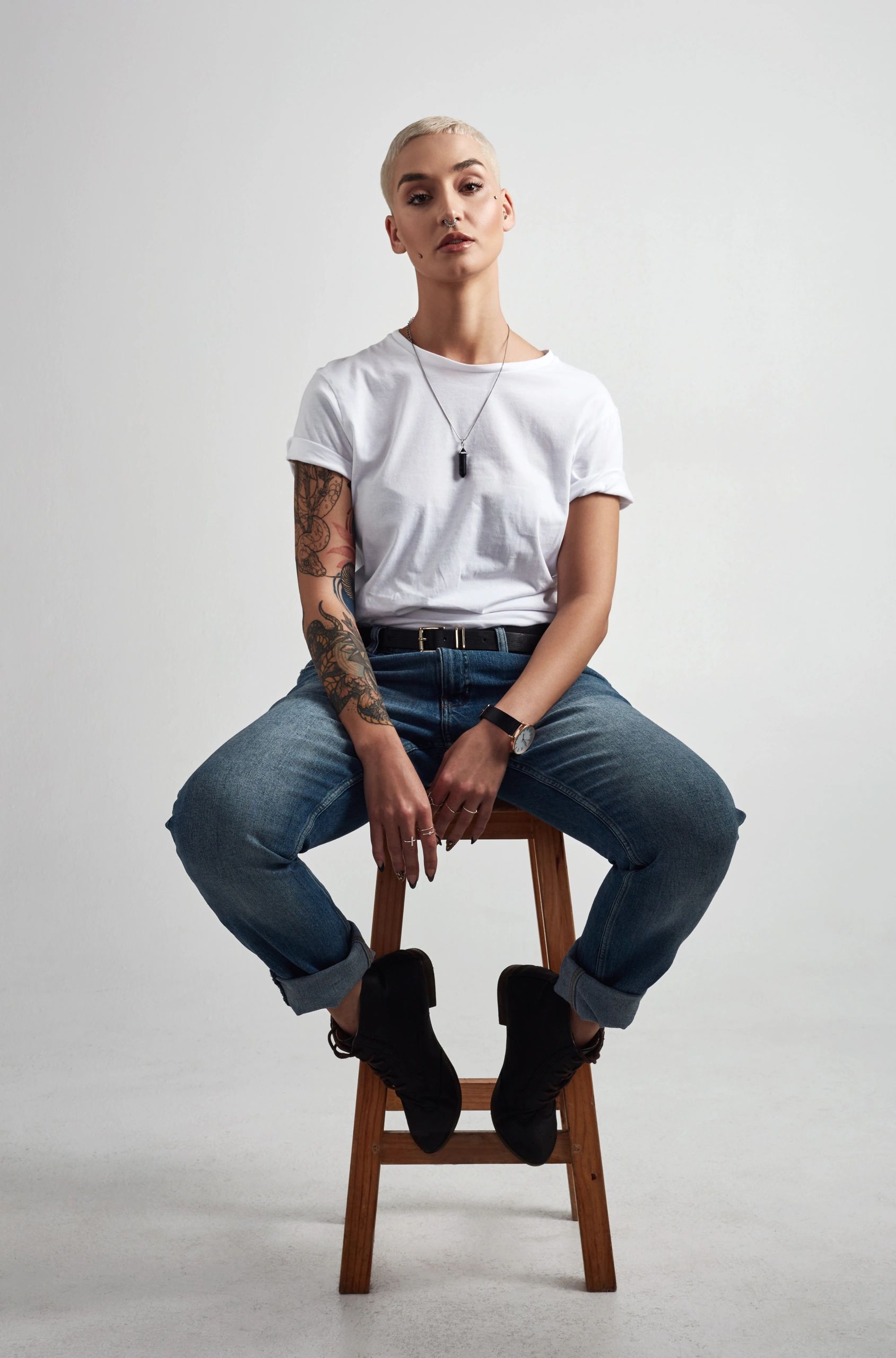 Stylish young woman in trend-forward streetwear posing on a stool