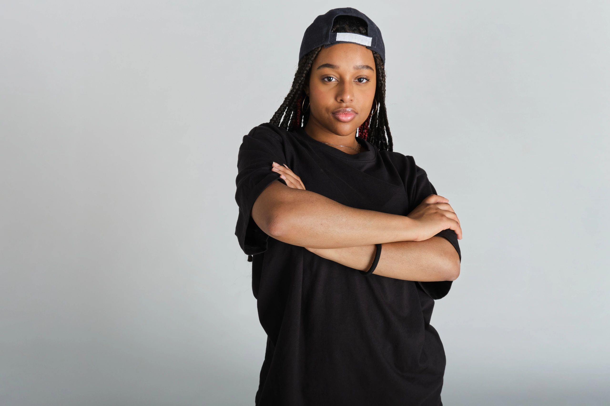 Confident young woman in black streetwear and cap