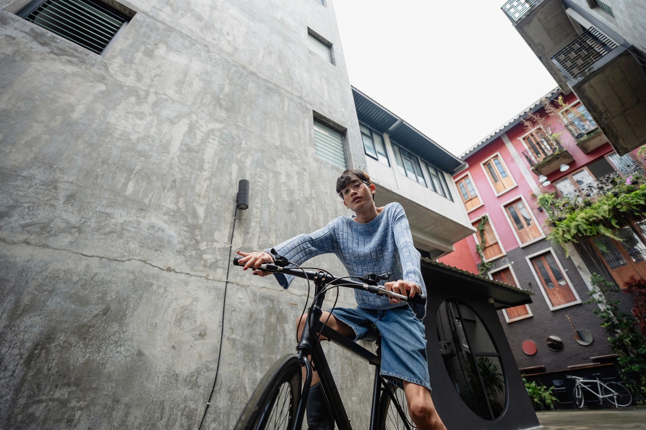 Stylish young man posing with a bicycle in an urban alley