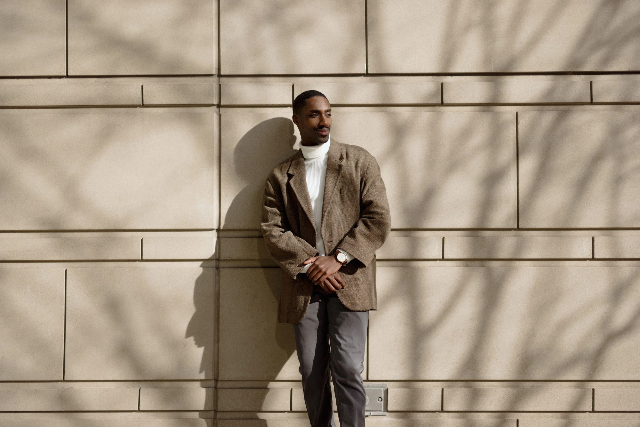 Young professional in a stylish outfit against a sunlit wall